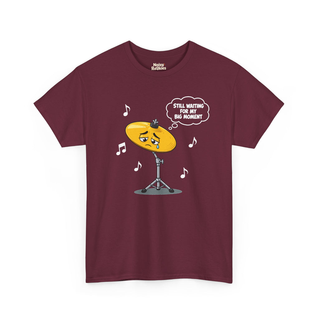 Dark-shirt design of a sad cartoon cymbal on a stand with a single tear, a thought bubble reading Still Waiting for My Big Moment, surrounded by music notes.